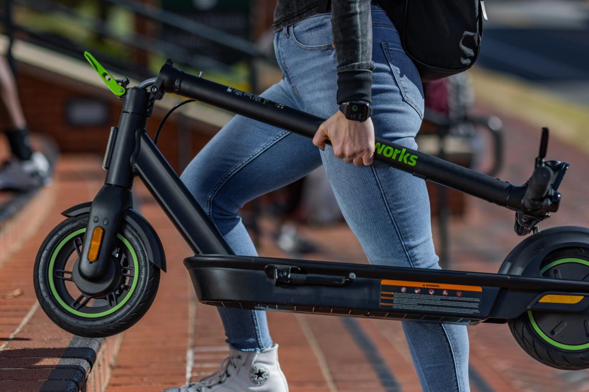 Greenworks electric scooter — commuter carrying a foldable scooter